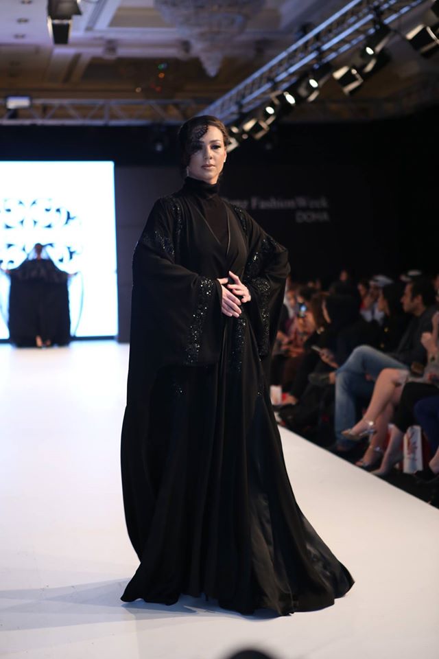 Desfilando com uma abaya (veste tradicional) e um pequeno véu de lado apenas simbólico. Como é um desfile de moda não caia bem o uso dos véus tradicionais.